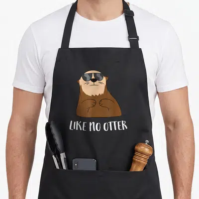 Tablier de cuisine noir avec une illustration de loutre portant des lunettes de soleil et le texte Like No Otter en blanc.