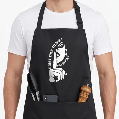 Tablier de cuisine noir avec illustration blanche d'un visage et message NE ME PARLE PAS, JE SUIS EN COLÈRE.