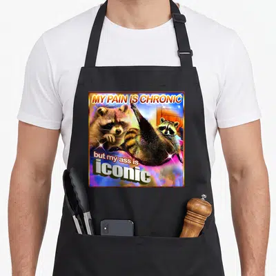 Tablier de cuisine noir avec illustration colorée d'un raton lèveuse et texte humoristique en anglais.