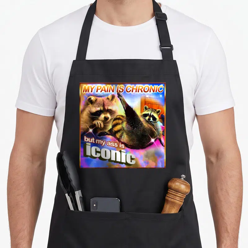 Tablier de cuisine noir avec illustration colorée d'un raton lèveuse et texte humoristique en anglais.