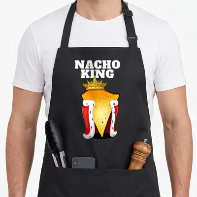 Tablier de cuisine noir avec un nacho couronné roi et une cape rouge portant l'inscription Nacho King.