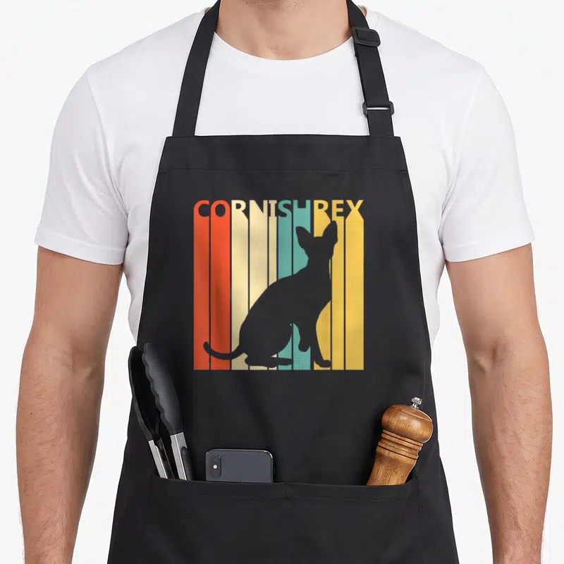 Tablier de cuisine noir avec silhouette de chat Cornish Rex sur fond de bandes colorées verticales orange, jaune et turquoise.