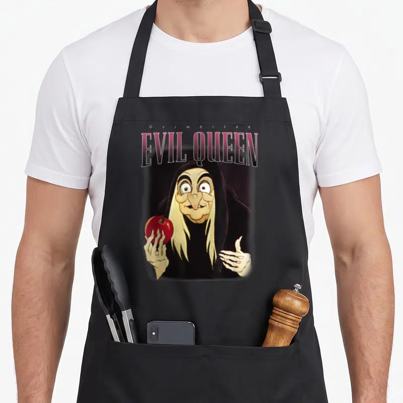 Tablier de cuisine noir avec illustration de la Reine méchante Grimhilde tenant une pomme rouge.