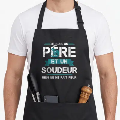 Tablier de cuisine noir avec inscription Je suis un père et un soudeur rien ne me fait peur en blanc et bleu.