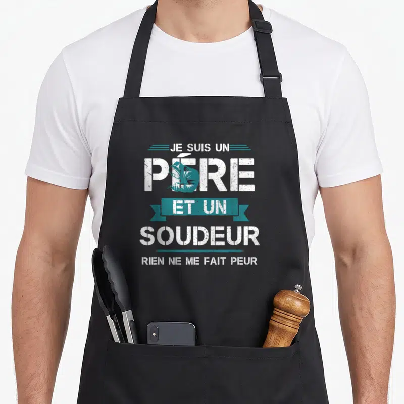 Tablier de cuisine noir avec inscription Je suis un père et un soudeur rien ne me fait peur en blanc et bleu.