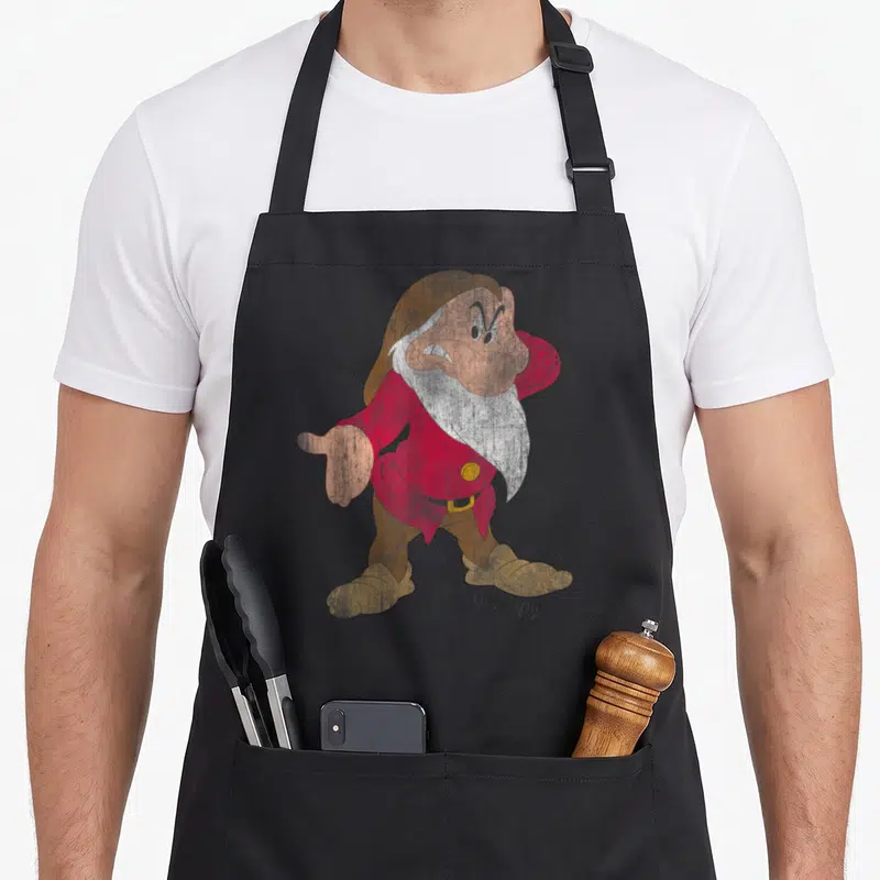 Tablier de cuisine noir avec illustration colorée du nain Grumpy en tenue rouge et marron.