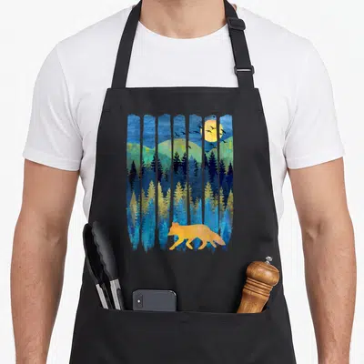 Tablier de cuisine noir avec illustration d'un renard orange dans une forêt bleue sous une lune jaune et des oiseaux en vol.