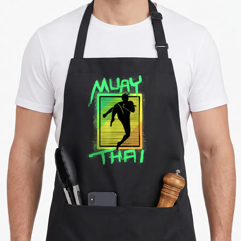 Tablier de cuisine noir avec silhouette Muay Thai et texte vert fluorescent sur fond dégradé jaune.