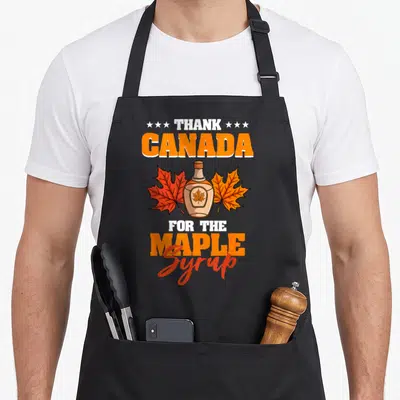 Tablier de cuisine noir avec un bocal de sirop d'érable et des feuilles d'érable orange et rouge.