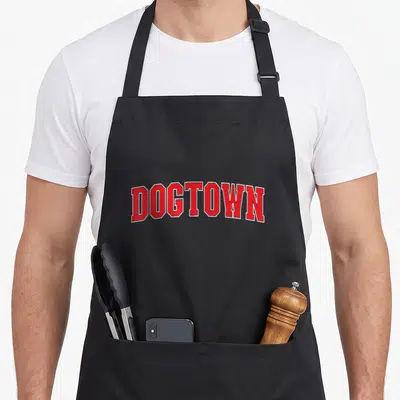 Tablier de cuisine noir avec l'inscription Dogtown en lettres rouges arquées style université.