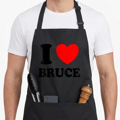Tablier de cuisine noir avec un grand cœur rouge et le texte I BRUCE en lettres noires épaisses.