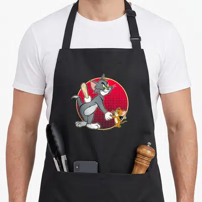 Tablier de cuisine noir avec Tom tenant une batte de baseball et Jerry souriant devant un fond rouge à pois.