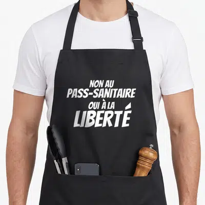 Tablier de cuisine noir avec le texte blanc Non au pass sanitaire oui à la liberté imprimé en gros caractères stylisés.