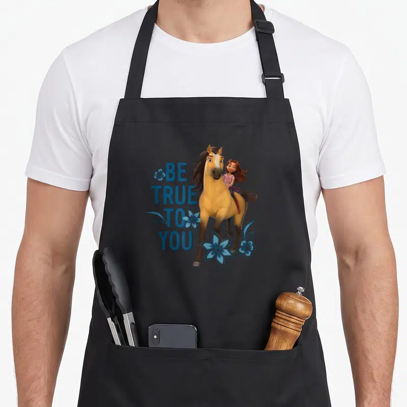Tablier de cuisine noir avec une illustration d'une fille et d'un cheval entourés de fleurs bleues et du texte Be True To You.