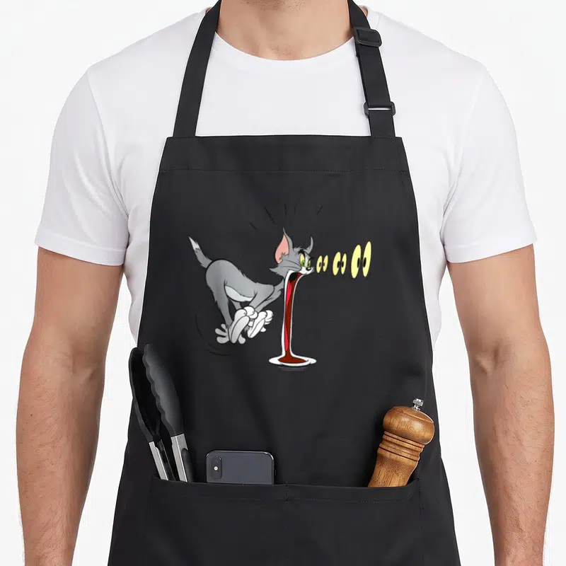 Tablier de cuisine noir avec Tom crachant des yeux jaunes en style cartoon comique