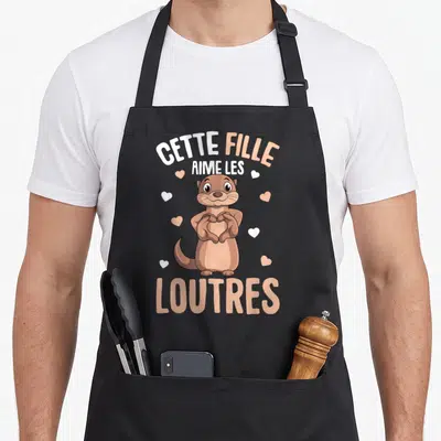 Tablier de cuisine noir avec une loutre marron formant un cœur avec ses pattes et des cœurs flottants autour.