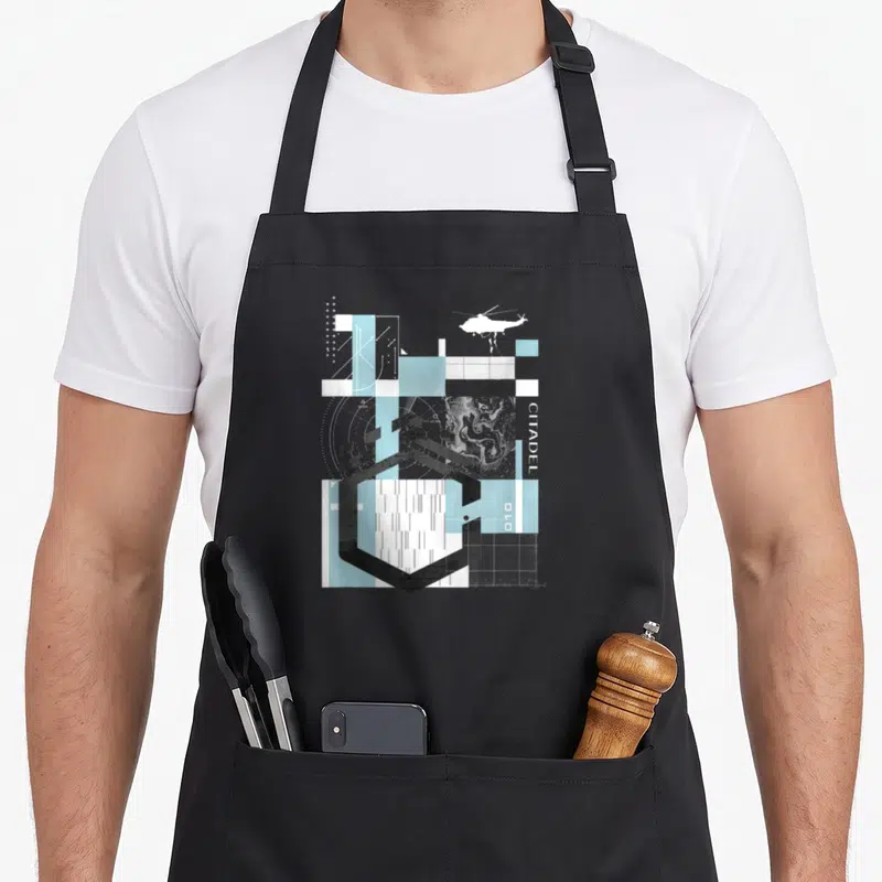 Tablier de cuisine noir avec collage géométrique bleu clair, hélicoptère blanc et texte citadel vertical.