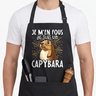 Tablier de cuisine noir avec illustration d'un capybara souriant et le texte Je m'en fous je suis un capybara en blanc.