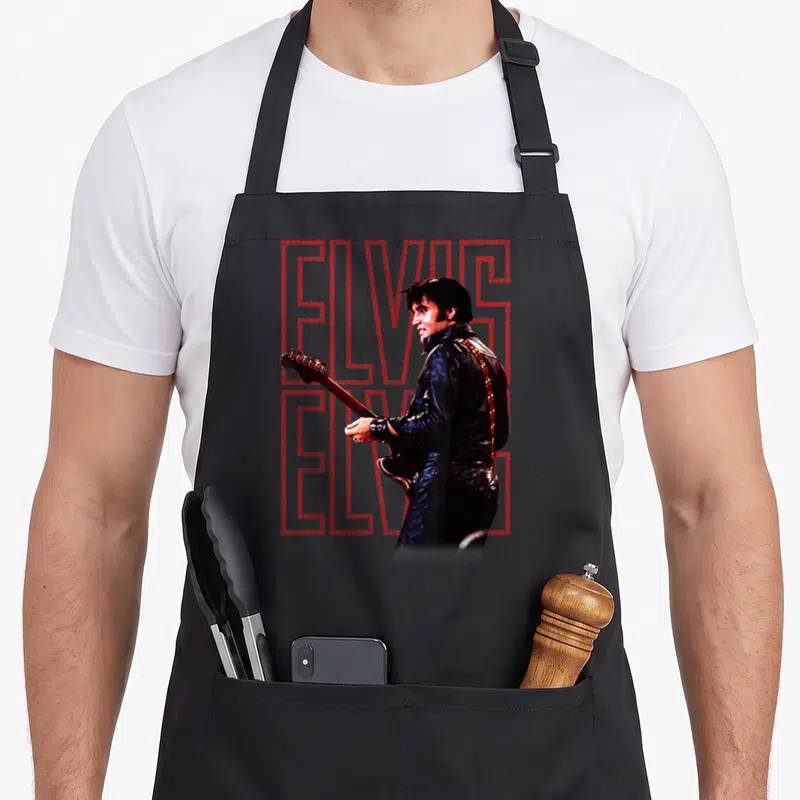Tablier de cuisine noir avec Elvis Presley en veste noire et texte ELVIS formingé de points rouges.