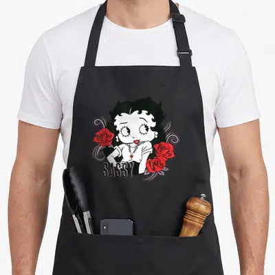 Tablier de cuisine noir avec Betty Boop, roses rouges et le mot SASSY imprimé au centre.