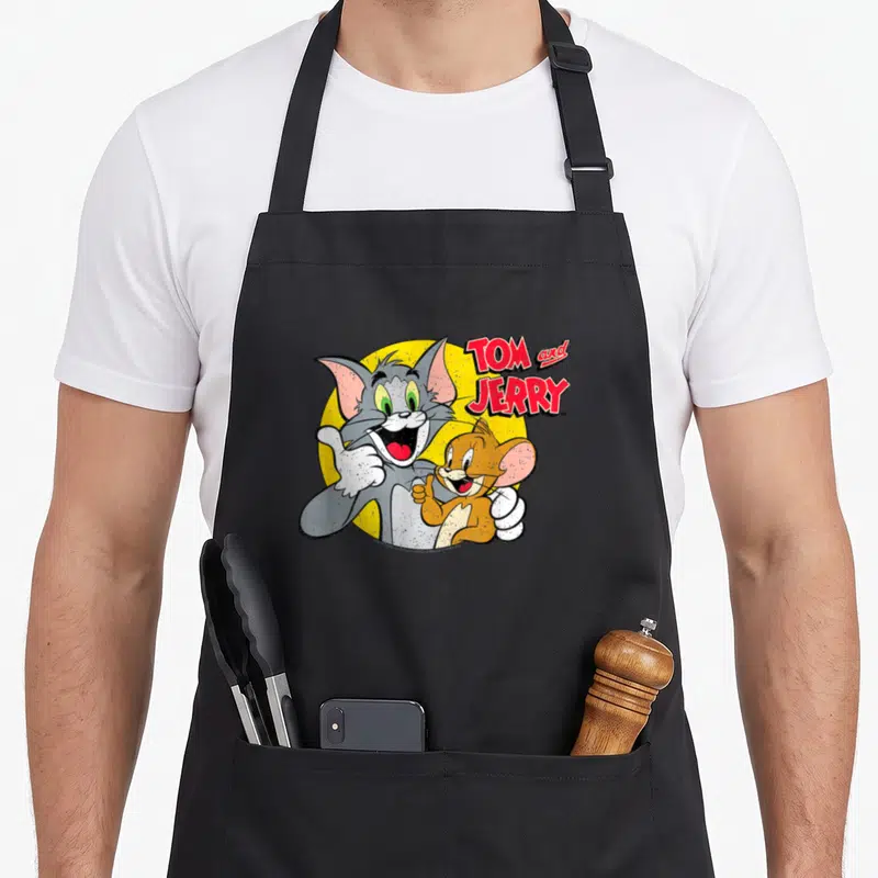 Tablier de cuisine noir avec Tom et Jerry souriants et les pouces levés devant un cercle jaune.