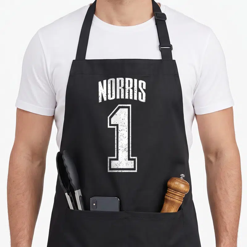 Tablier de cuisine noir avec l'inscription NORRIS au-dessus d'un grand chiffre 1 blanc à l'aspect vieilli.