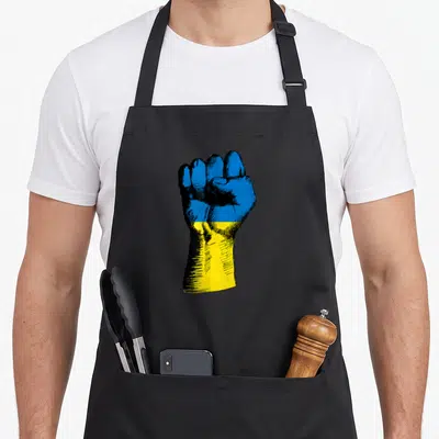 Tablier de cuisine noir avec un poing levé aux couleurs du drapeau ukrainien en style gravure.