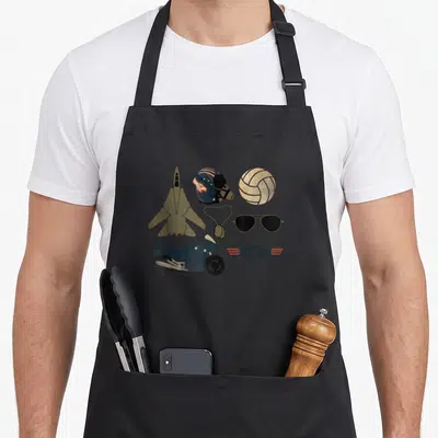 Tablier de cuisine noir avec illustration d'avion de chasse, casque, lunettes aviateur, moto et logo Top Gun en style vintage.