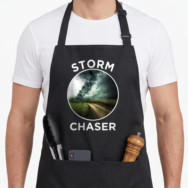 Tablier de cuisine noir avec une tornade photographiée dans un cercle blanc et les mots STORM CHASER en lettres capitales au-dessus et en dessous.