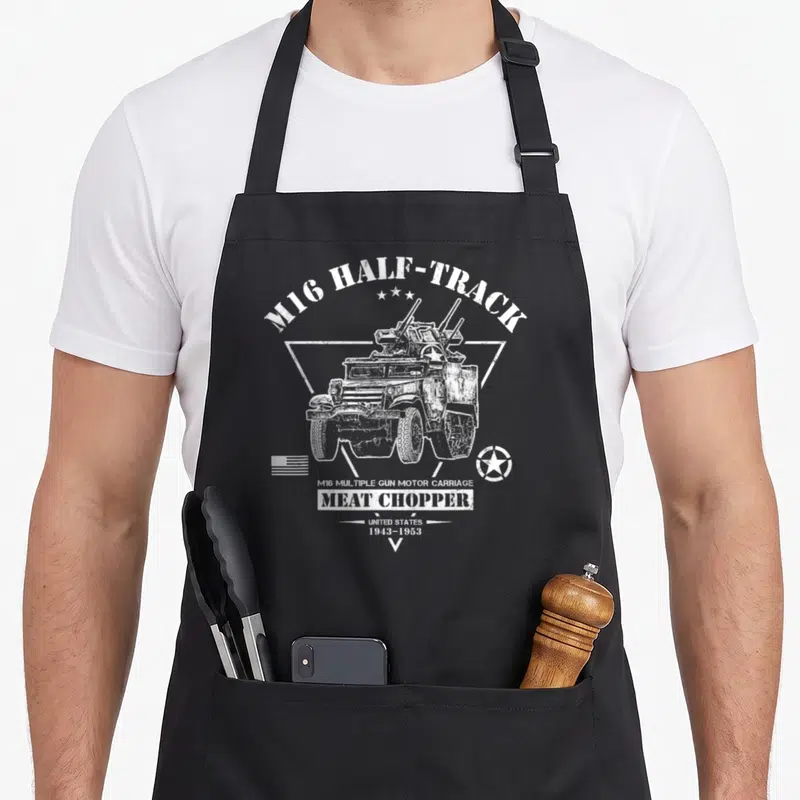 Tablier de cuisine noir avec illustration blanche d'un véhicule militaire M16 Half-Track et texte vintage.