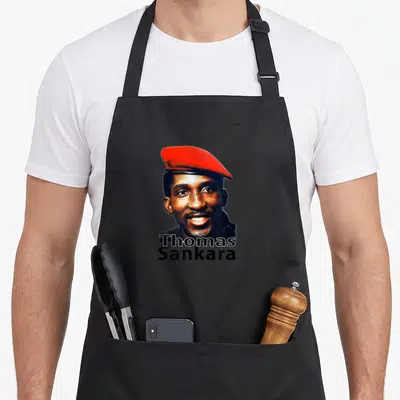Tablier de cuisine noir avec le portrait souriant de Thomas Sankara portant une béret rouge et son nom en lettres noires.