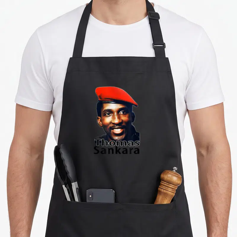 Tablier de cuisine noir avec le portrait souriant de Thomas Sankara portant une béret rouge et son nom en lettres noires.