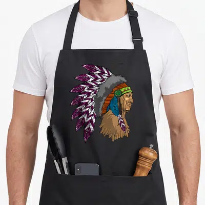 Tablier de cuisine noir avec illustration colorée d'un chef amérindien portant une coiffe de plumes violettes et blanches.