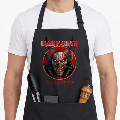 Tablier de cuisine noir avec le visage démoniaque d'Eddie et le titre Senjutsu en typographie métallique rouge.