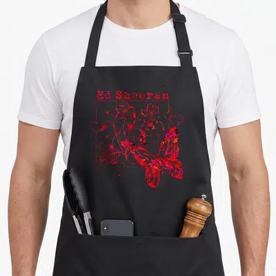 Tablier de cuisine noir avec illustration rose Ed Sheeran, papillon, cœurs et fleurs stylisées.