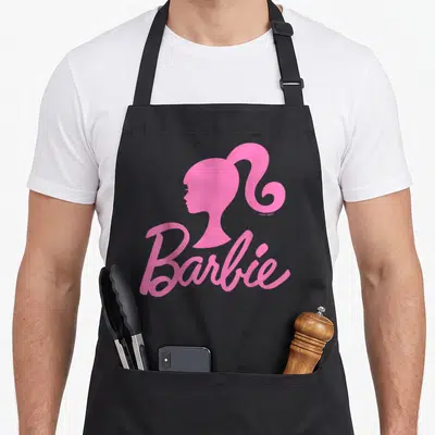 Tablier de cuisine noir avec le logo Barbie rose et le profil stylisé de la poupée en haut à droite.