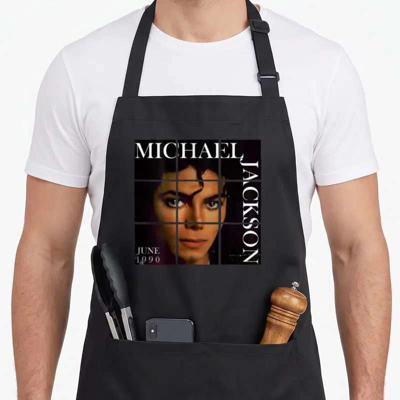 Tablier de cuisine noir avec portrait en grille de Michael Jackson et texte blanc June 1990 sur le devant.