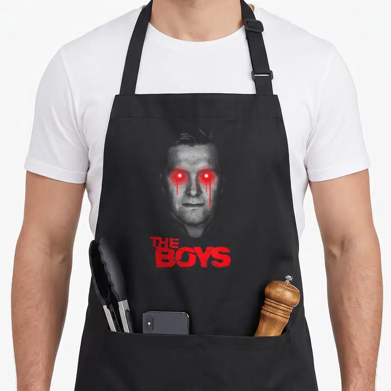 Tablier de cuisine noir avec portrait d'Homelander aux yeux rouges et texte The Boys en rouge.