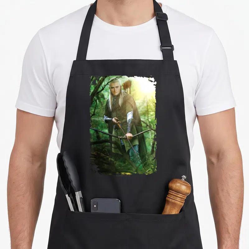 Tablier de cuisine noir avec une illustration colorée de Legolas tenant un arc dans un bois ensoleillé.