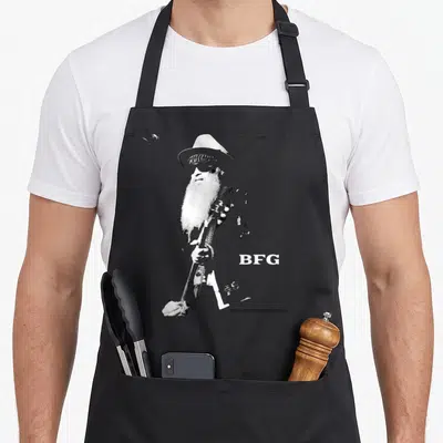 Tablier de cuisine noir avec illustration monochrome de Billy F Gibbons BFG tenant une guitare et portant un chapeau.