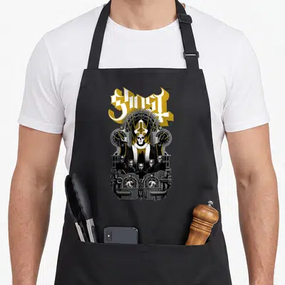 Tablier de cuisine noir avec illustration gothique représentant un prêtre squelette et le logo Ghost en lettres dorées.