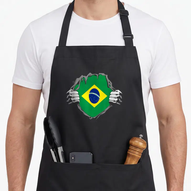 Tablier de cuisine noir avec illustration de mains déchirant le tissu pour révéler le drapeau du Brésil
