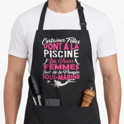 Tablier de cuisine noir avec inscription rose et blanche sur la plongée sous-marine et silhouettes de nageuses.