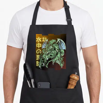Tablier de cuisine noir avec illustration vert clair d'un monstre aquatique aux ailes et symboles japonais sur fond texturé orange et brun.