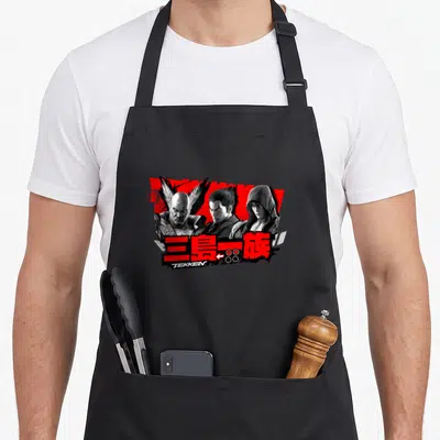 Tablier de cuisine noir avec illustration des personnages Tekken et le logo de la famille Ishima en rouge et blanc.