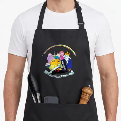 Tablier de cuisine noir avec illustration colorée d'un groupe de personnages de dessin animé sous un arc-en-ciel et une banderole textuelle.