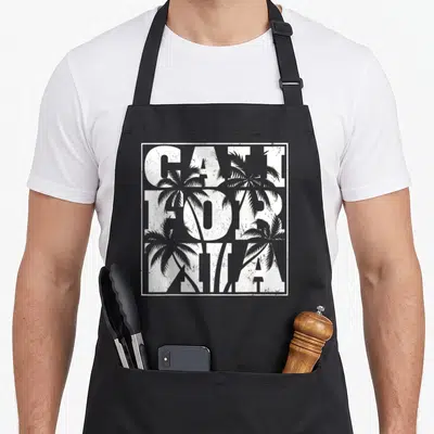 Tablier de cuisine noir avec inscription California et silhouettes de palmiers en blanc.