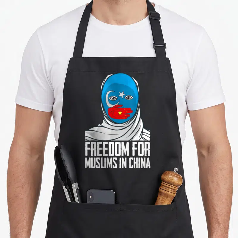Tablier de cuisine noir avec illustration d'un visage masqué bleu et texte blanc sur fond uni.