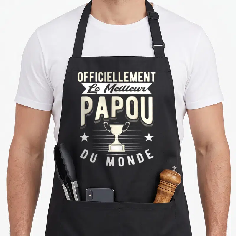 Tablier de cuisine noir avec inscription « Officiellement Le Meilleur Papou Du Monde » et illustration de trophée blanc.