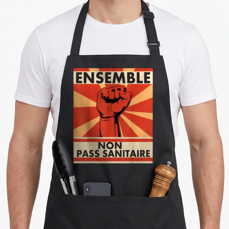 Tablier de cuisine noir avec illustration poing levé rouge et texte Ensemble NON PASS SANITAIRE imprimé en noir.